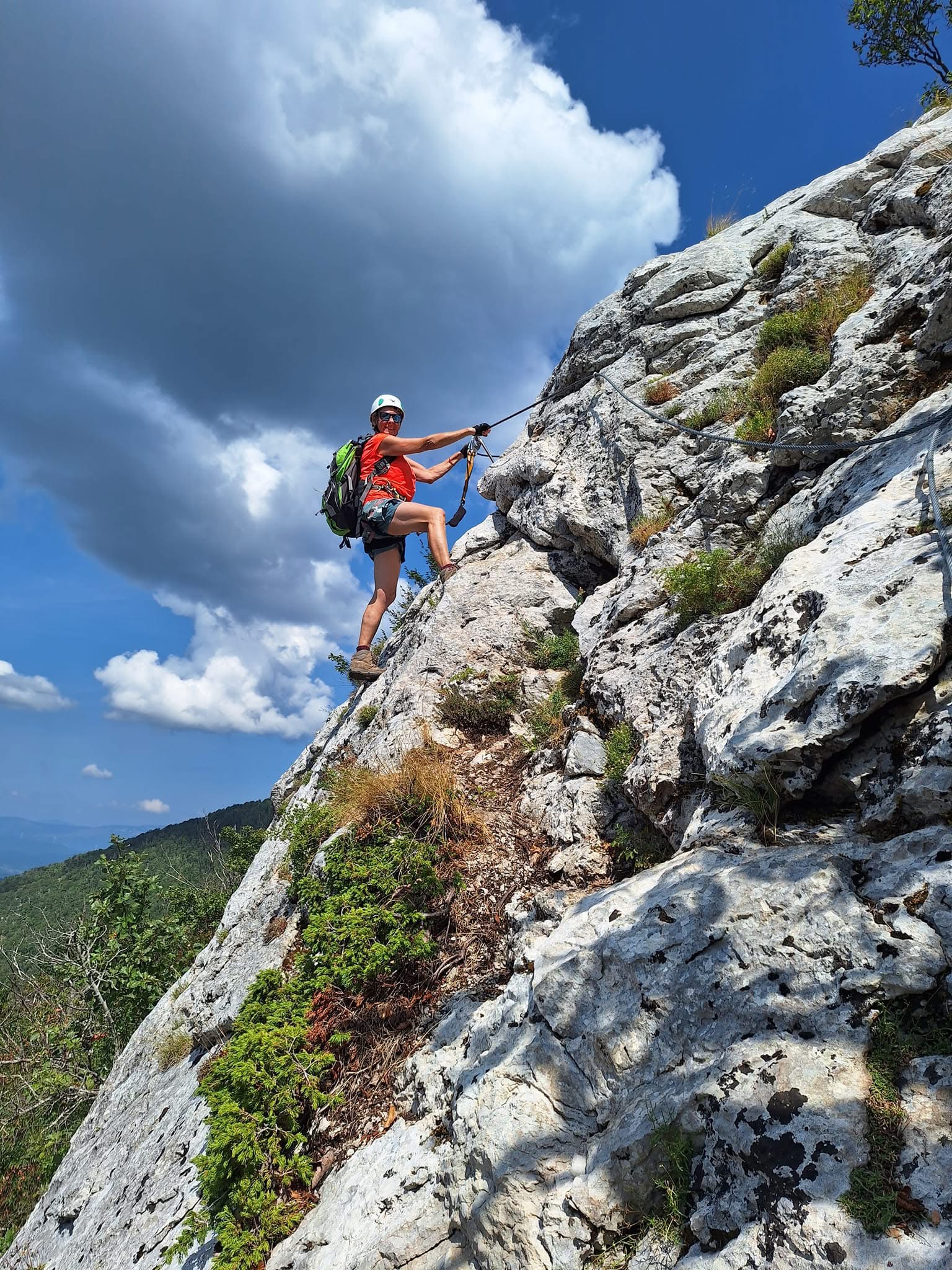 Wspinaczka na trasie via ferrata, zabezpieczonie lonżą i kaskiem na skalnej ścianie